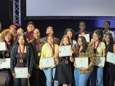 students holding certificates on stage